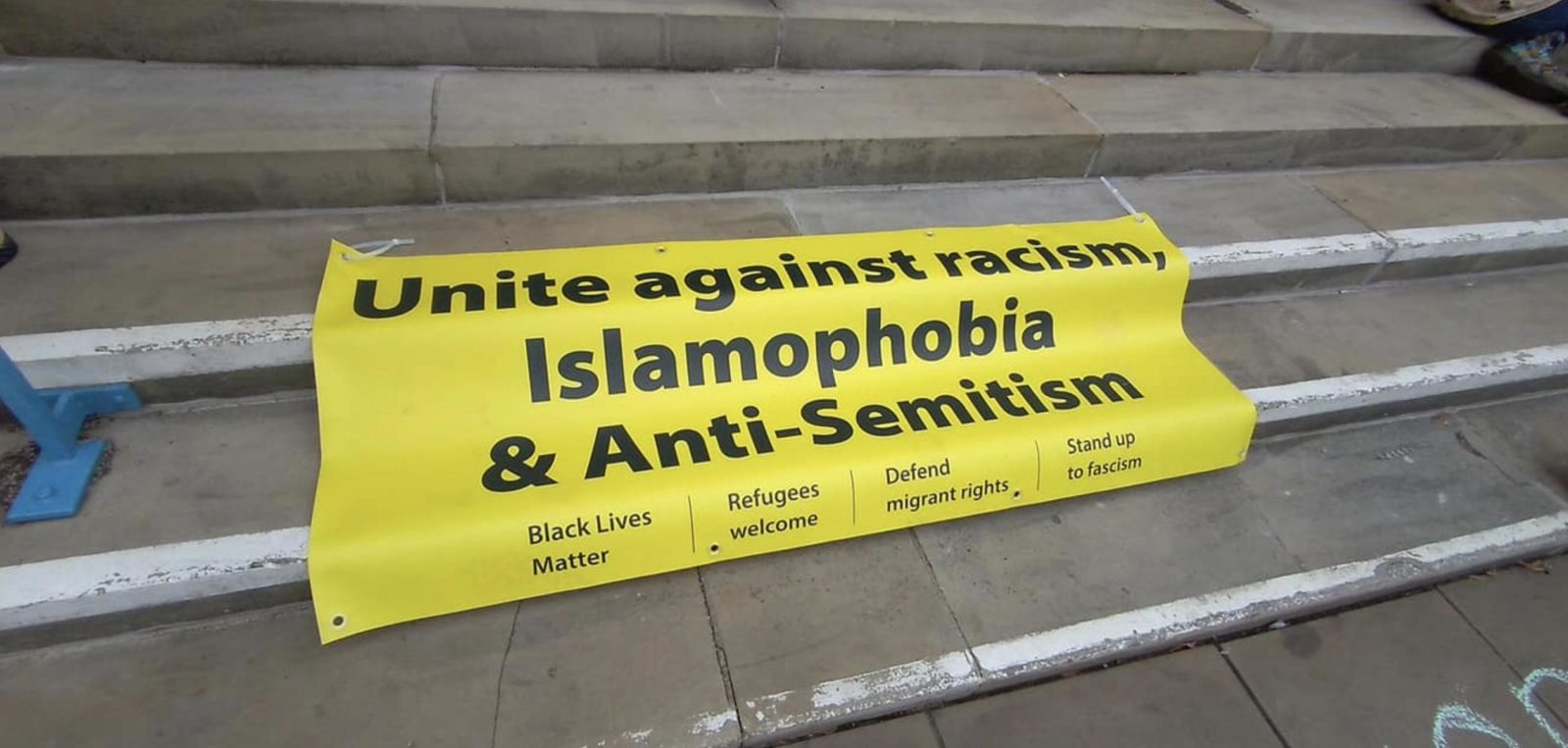 Image of a banner on steps which reads "Unite against racism, Islamophobia & Anti-Semitism