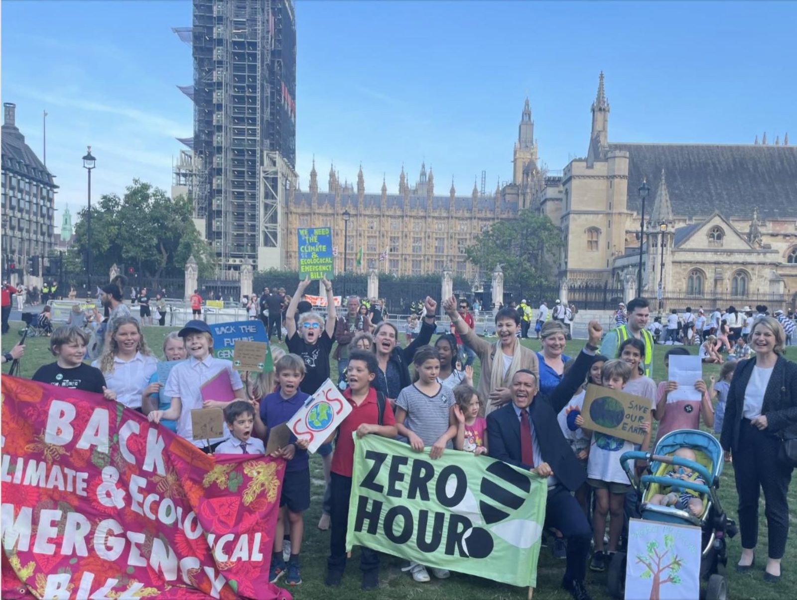 Clive with a group of people holding banners outside the Houses of Parliament